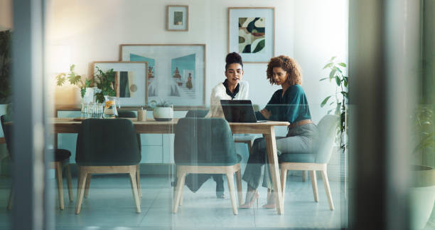 Two colleagues reviewing work together in a bright office